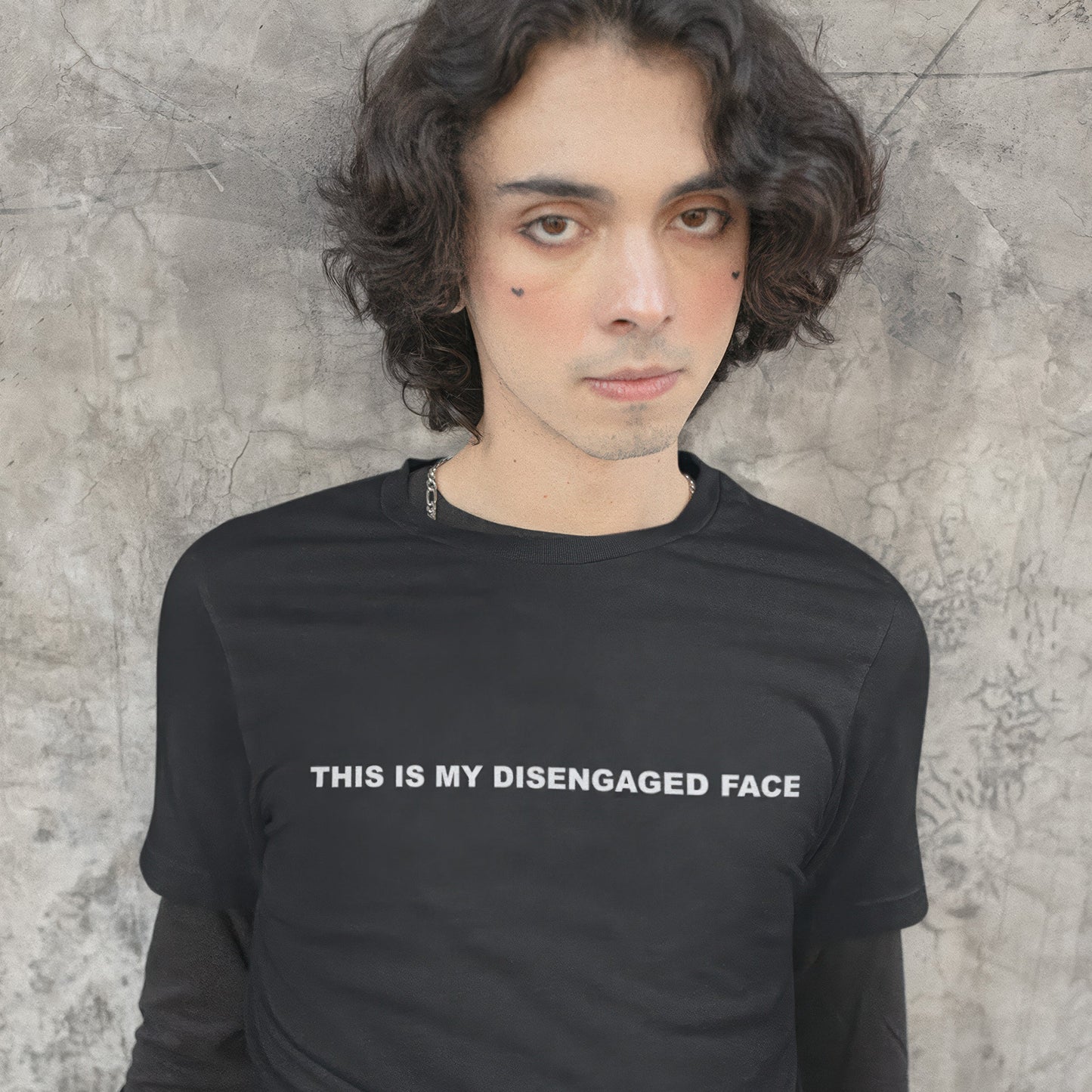 Person wearing a black t-shirt with text 'THIS IS MY DISENGAGED FACE' against a textured wall.