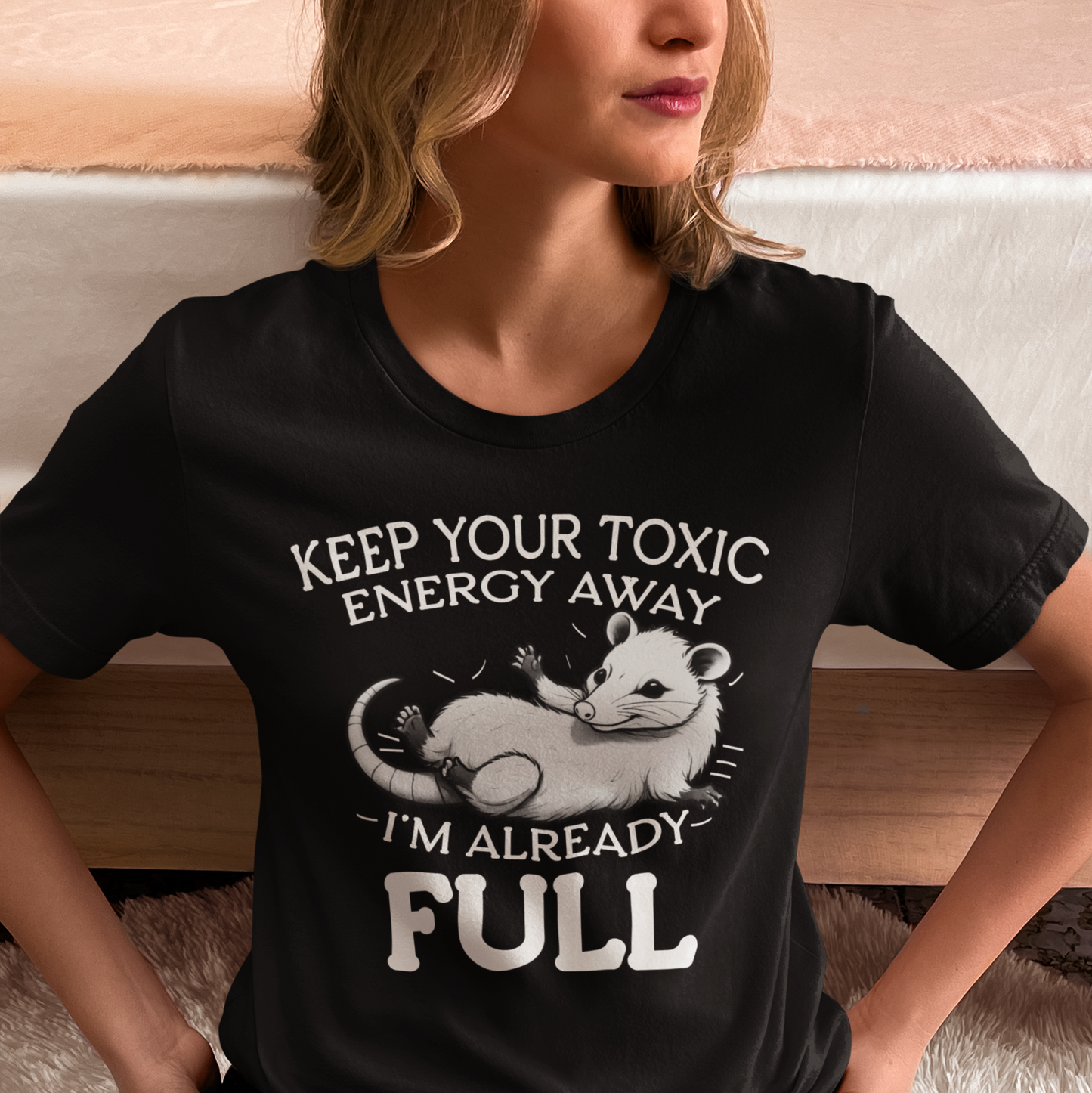 Person wearing a black t-shirt with a graphic and text, sitting on a couch.
