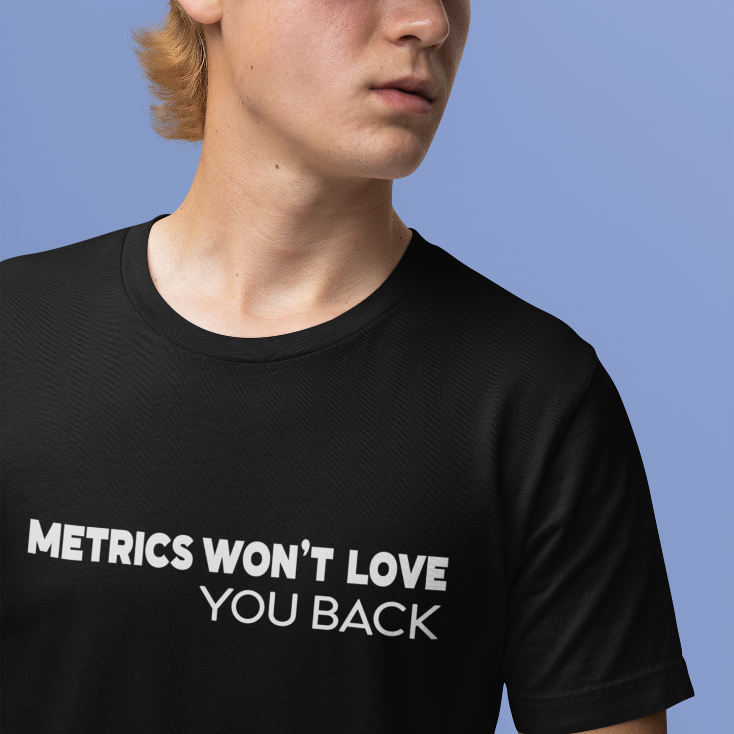 Person wearing a black t-shirt with 'METRICS WON'T LOVE YOU BACK' text against a blue background