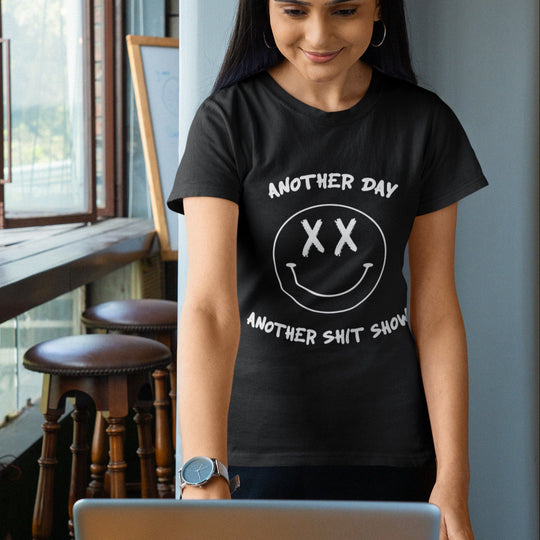 Woman wearing a black t-shirt with white text and smiley face design, sitting at a desk.