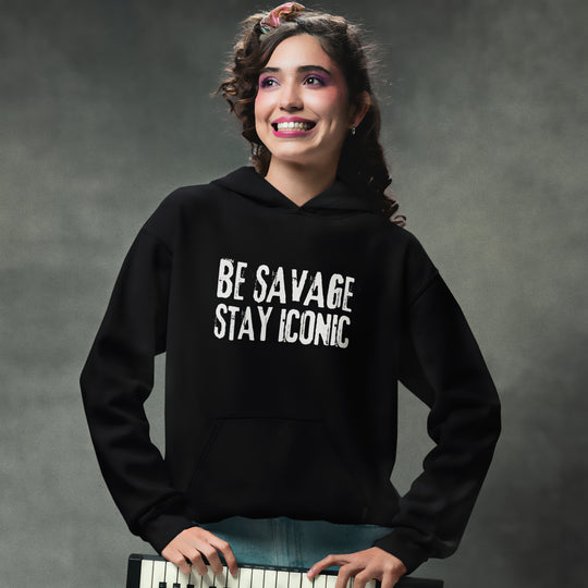 Person wearing a black hoodie with 'BE SAVAGE STAY ICONIC' text, standing against a gray background.