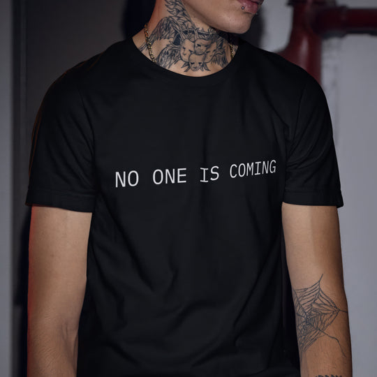 Person wearing a black t-shirt with 'NO ONE IS COMING' text