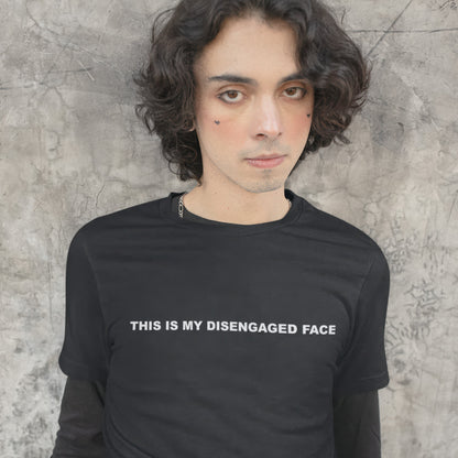 Person wearing a black t-shirt with text 'THIS IS MY DISENGAGED FACE' against a textured wall.
