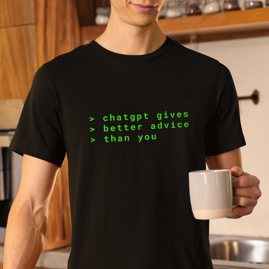 Person wearing a black t-shirt with green text in a kitchen holding a white mug.