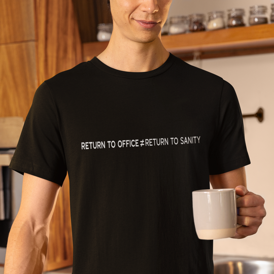 Person wearing a black t-shirt with text in a kitchen holding a mug.