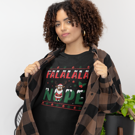 Person wearing a black t-shirt with 'FALALALA NOPE' text, holding a plaid jacket indoors.