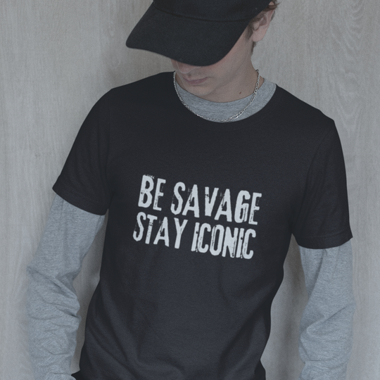 Person wearing a black t-shirt with 'BE SAVAGE STAY ICONIC' text, gray long-sleeve shirt underneath, and black cap.