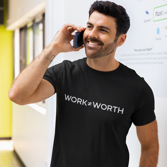 Man wearing a black 'WORK=WORTH' t-shirt in an indoor setting.