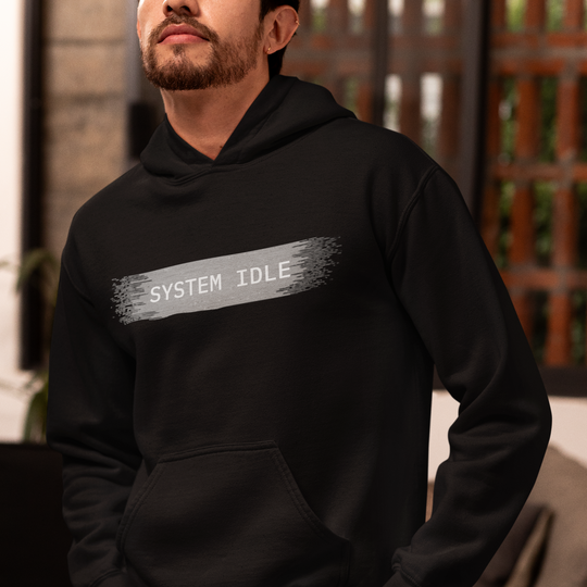 Person wearing a black hoodie with 'SYSTEM IDLE' text in a casual setting