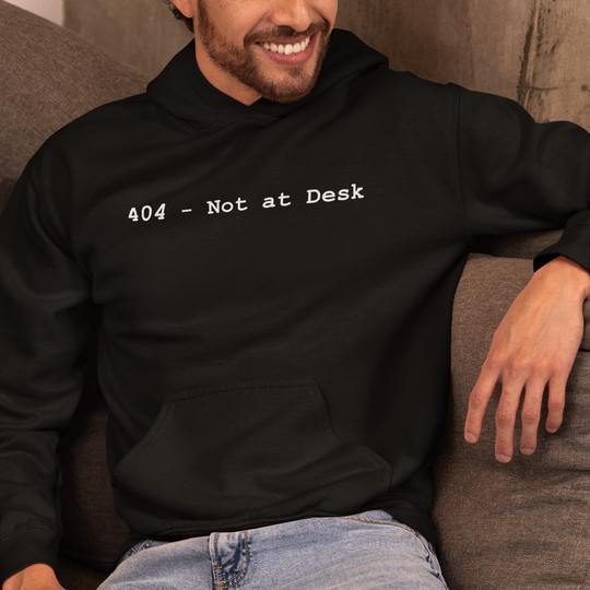 Man wearing a black hoodie with '404 - Not at Desk' text, sitting on a couch.